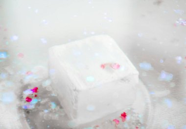 A whimsical white sugar cube amidst colorful sprinkles. clipart