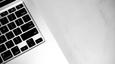 Close-up of a laptop keyboard on a light-colored marble surface. clipart