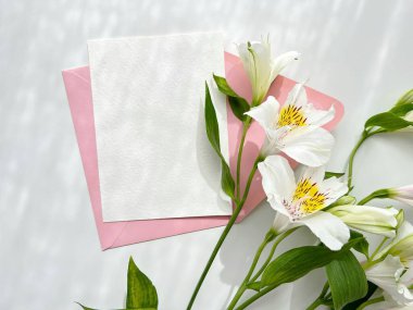 Elegant white flowers with pink envelopes and a blank card for invitations or messages. clipart