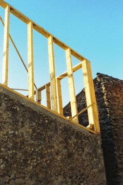 Wooden frame structure against a clear blue sky during construction. clipart