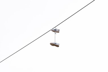 A pair of sneakers hanging from a power line against a clear sky. clipart