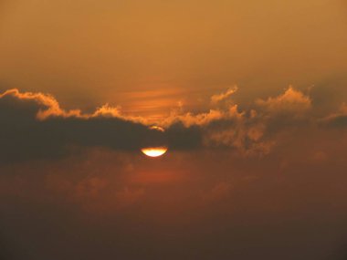 Altın gün batımı kısmen bulutlar tarafından gizlenmiş, sakin bir atmosfer yaratıyor..