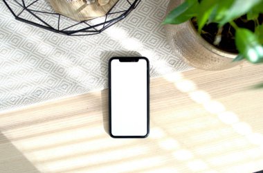 A sleek smartphone on a wooden surface surrounded by greenery. clipart