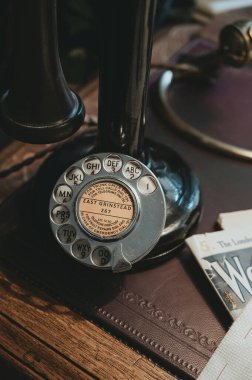 Close-up of a vintage rotary phone dial with a brown leather background. clipart