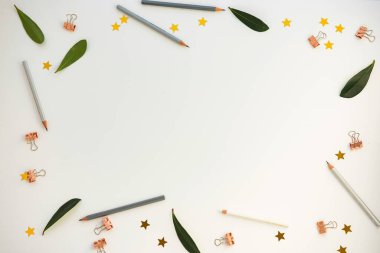 Creative workspace layout with leaves, colorful pencils, and decorative stars. clipart