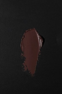 A rich, dark chocolate smear on a textured black background. clipart