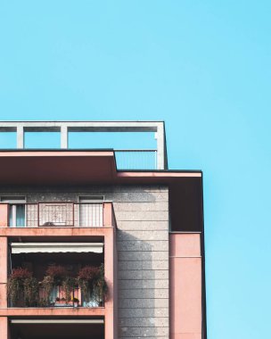 Modern pink apartment building against a clear blue sky. clipart