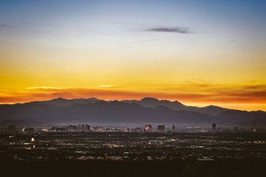 Stunning sunset over a city skyline with mountains in the background. clipart