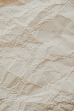 Close-up of crumpled beige paper texture with unique patterns and shadows. clipart