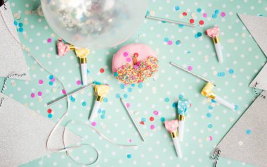 Colorful party scene featuring a pink donut and festive decorations. clipart