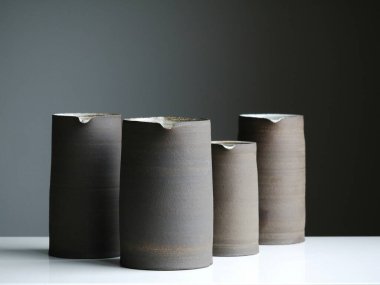 Four elegant ceramic vases in earthy tones on a minimalistic surface. clipart