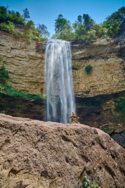 Falls Creek Şelalesi Tennessee 'deki Falls Creek Eyalet Parkı' nda büyük bir kayanın üzerinde küçük bir kaya cairn ile..