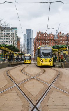A pair of yellow Metrolink trams seen in St Peters Square travelling in opposite directions in February 2023.