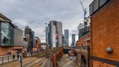 A multi image panorama showing the varying types of buildings and architecture between the tram ramp from Manchester city centre to Deansgate seen in February 2023.