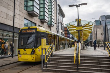 A yellow and grey Metrolink tram stopping at Corporation Street in Greater Manchester seen in February 2023.