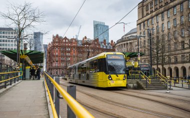 Two trams waiting at a stop in St Peters Square, Manchester seen in February 2023.