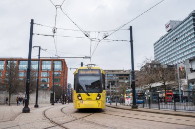 A closeup of a yellow Metrolink tram turning at Picadily Gardens in Manchester in February 2023.