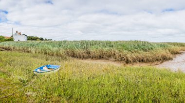 Brancaster Stadyumu 'nda kıyıya bağlı bir teknenin çok görüntülü manzarası ve Kuzey Norfolk sahilindeki alçak gelgitte uzun otların üzerinde oturuyordu..