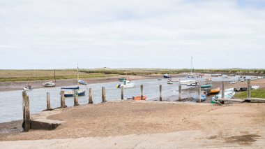 Burnham Overy Staithe 'deki tuhaf rıhtım. Ağustos 2023' te Kuzey Norfolk sahilinde çekilmiş renkli teknelerle dolu..