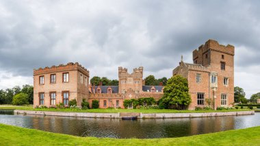 Ağustos 2023 'te Norfolk' taki Oxburgh Hall 'u çevreleyen hendeğe demirlemiş bir teknenin çok görüntülü manzarası..