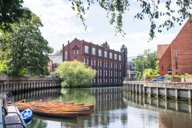 Norwich Üniversitesi 'nin Norwich' te Wensum nehrinin kıyısında çekilen resmi, Ağustos 2023 'te birkaç küçük zevk teknesinin arkasında ele geçirildi..