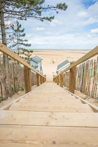 Wooden steps lead holiday makers down to beach huts at Wells next the Sea on the Norfolk coastline seen in August 2023.