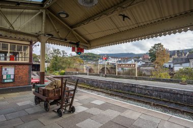 Llangollen tren istasyonundaki platformda Llangollen Köprüsü ve Dee nehrinin arka planında 27 Ekim 2023 'te çekilmiş eski davalar..