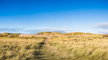 Liverpool yakınlarındaki Formby 'de kıyı şeridi boyunca uzanan yüksek kum tepelerinin üzerindeki açık mavi gökyüzünün çok görüntülü manzarası..