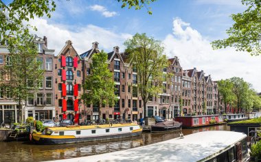 Hollanda, Amsterdam 'da 27 Mayıs 2024' te görülen demirli kayıkhanelerle dolu Prinsengracht kanalı renkli kepenkleri olan güzel kasaba evleri.