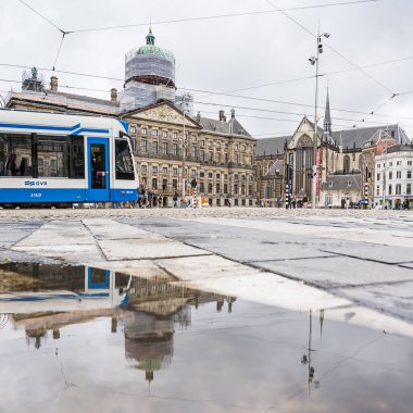 29 Mayıs 2024 'te Hollanda' nın Amsterdam kentinde görülen, arkasında Kraliyet Sarayı ve Yeni Kilise bulunan bir tramvayın yansımaları..