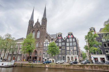 De Krijtberg chuch, 26 Mayıs 2024 'te Hollanda' nın Amsterdam kentindeki Singel Kanalı 'nın üzerinde gökdelenler hayal etti..