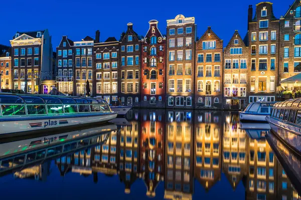 stock image The charming and uneven gingerbread houses at Damrak pictured at nightfall in Amsterdam, the Netherlands on 26 May 2024.