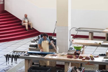 Bir adam bıçağını Mercado dos Lavradores pazarında satılık bir Black Scabbard balığı hazırlamak için kullanıyor. Fotoğraf 6 Ağustos 2024 'te Funchal, Madeira' nın merkezinde çekilmiştir..