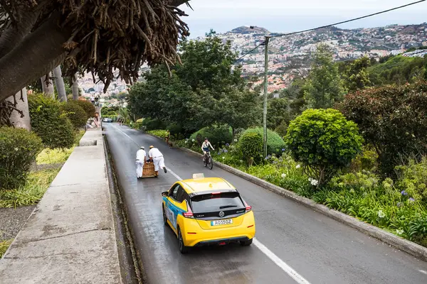 stock image A yellow taxi seen on 31 July 2024 following a toboggan downhill made of wicker pictured from Monte, Madeira.