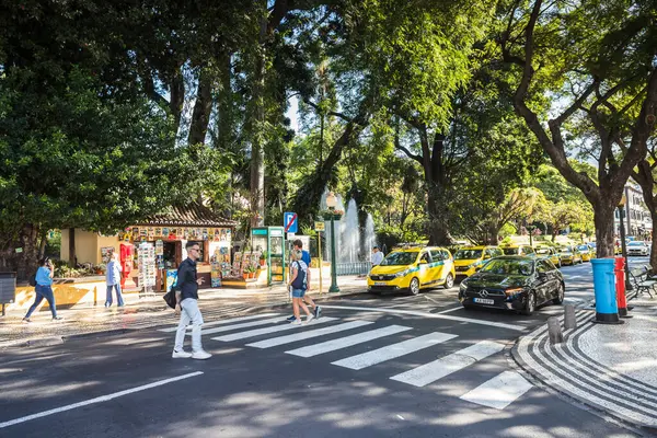 stock image A colourful street in Funchal next to a park featuring yellow taxis and both red and blue post boxes.  Seen on 6 August 2024 on Madeira Island, Portugal.