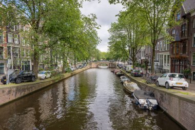 Hollanda, Amsterdam 'ın göbeğinde bulunan Reguliersgracht Kanalı' nda 28 Mayıs 2024 'te park halindeki araba ve teknelerin kıyılara demirlediği resmedildi..