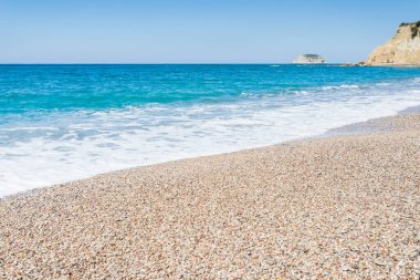 Dalgalar, Yunanistan 'ın Rodos kentinde mavi gökyüzünün altında görülen Fourni Sahili' nde çakıl taşlarıyla karşılaşıyor.
