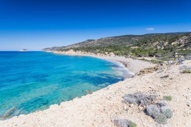 Mavi denizin Rodos 'taki Fourni Sahili' nin etrafındaki kum, çakıl ve kayalarla buluşmasının geniş bir görüntüsü..
