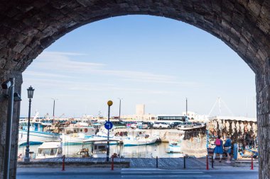 Turistler, 14 Nisan 2025 'te Yunanistan' ın Rodos kentindeki limanın kenarına demirlemiş yerel bir tekneye bakıyorlar..