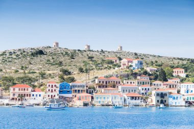 Yunanistan 'ın Chalki Adası etrafındaki turkuaz sularda 17 Nisan 2025' te üç eski yel değirmeninin altında balıkçı tekneleri görülüyor..
