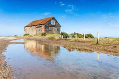 Kuzey Norfolk kıyısındaki Thornham 'daki Kömür Ambarı' nın yansımaları yüksek gelgitin bıraktığı bir su birikintisinden..