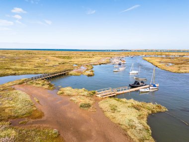 Morston Quay 'in 14 Ağustos 2025' te Norfolk 'ta görülen dalgalı su kanalları içindeki küçük teknelerin hava görüntüsü..