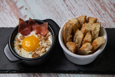 Recipe Oeuf cocotte with fresh cream sauce, Roquefort and walnuts, ham chips, toasted bread sticks. High quality photo