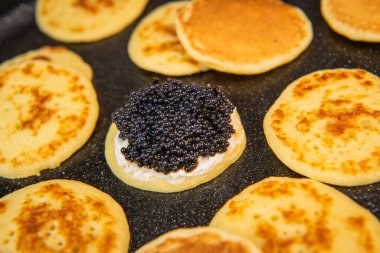 Siyah havyar ve krem peynirli jaluziler, şenlikli bir tabakta, mini gözlemeler, zarif bir aperatif, kaliteli bir fotoğraf.