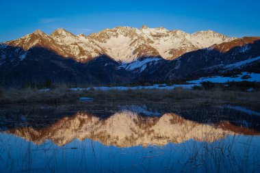 Sunset over the Pyrenees mountains with the reflection of the peaks in the water of the lake High quality 4k footage clipart