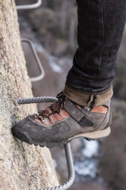 Emniyet kemeri takmış bir adam, demir parantezlere kancaları takıyor, kayalara tırmanıyor, aktif insan yaşam tarzı, dağcılık, pireneler dağlarında viaferrata, yüksek kaliteli fotoğraf.