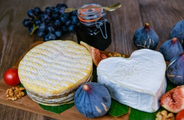 Selection of French cheeses from Normandy, AOP, Livarot, Neufchatel, Pont leveque, Rye bread, figs, walnuts, grapes, elderberry gelee. High quality photo clipart