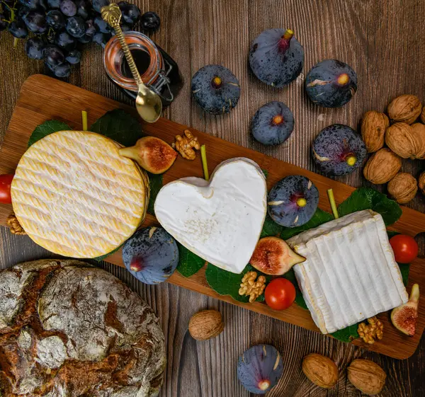 Stock image Selection of French cheeses from Normandy, AOP, Livarot, Neufchatel, Pont leveque, Rye bread, figs, walnuts, grapes, elderberry gelee. High quality photo