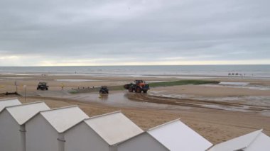 Plaj, Cabourg şehri, Normandiya, plaj kulübelerinin yakınına kum taşıyan bir kepçe, yüksek kalite 4K görüntü.