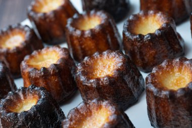 Caneles de Bordeaux, beyaz masa arkaplanlı geleneksel Fransız tatlısı, yüksek kaliteli fotoğraf.